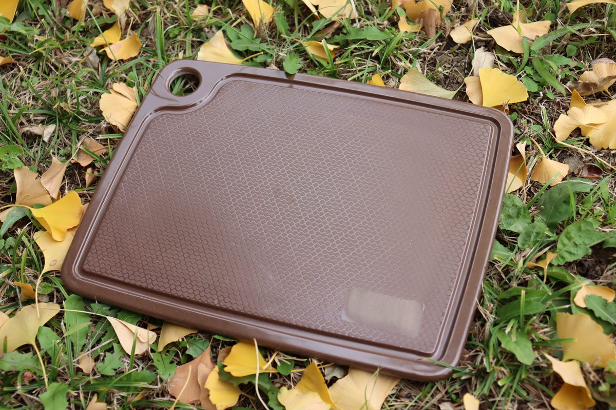 Brown rice husk chopping board photographed outdoors — private label eco tableware in a custom-matched deep colorway